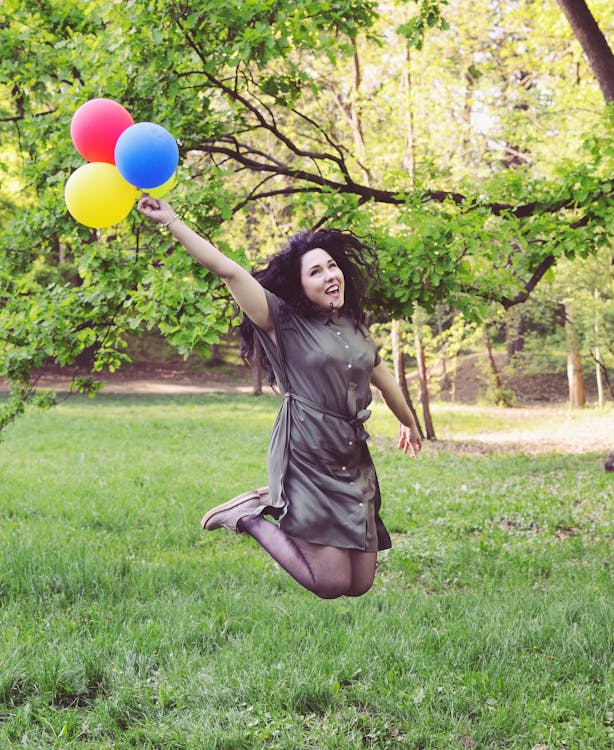 Free Woman Jumping While Holding Four Balloons Stock Photo