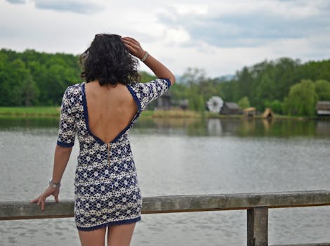 在罗马尼亚锡比乌，一位穿着时髦的女士站在风景秀丽的湖边，欣赏夏日美景