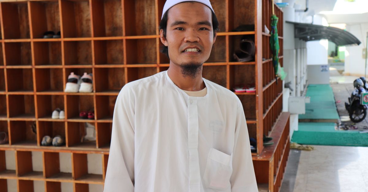 Thobe Rack A Man in White Thobe Standing Near Wooden Shoe Rack while Smiling at ...