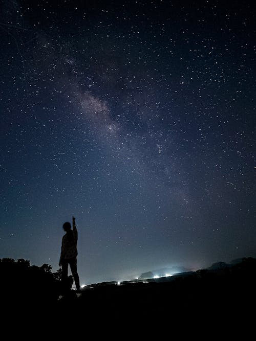 Free Silhouette of Person Standing Pointing Finger on Starry Night Stock Photo