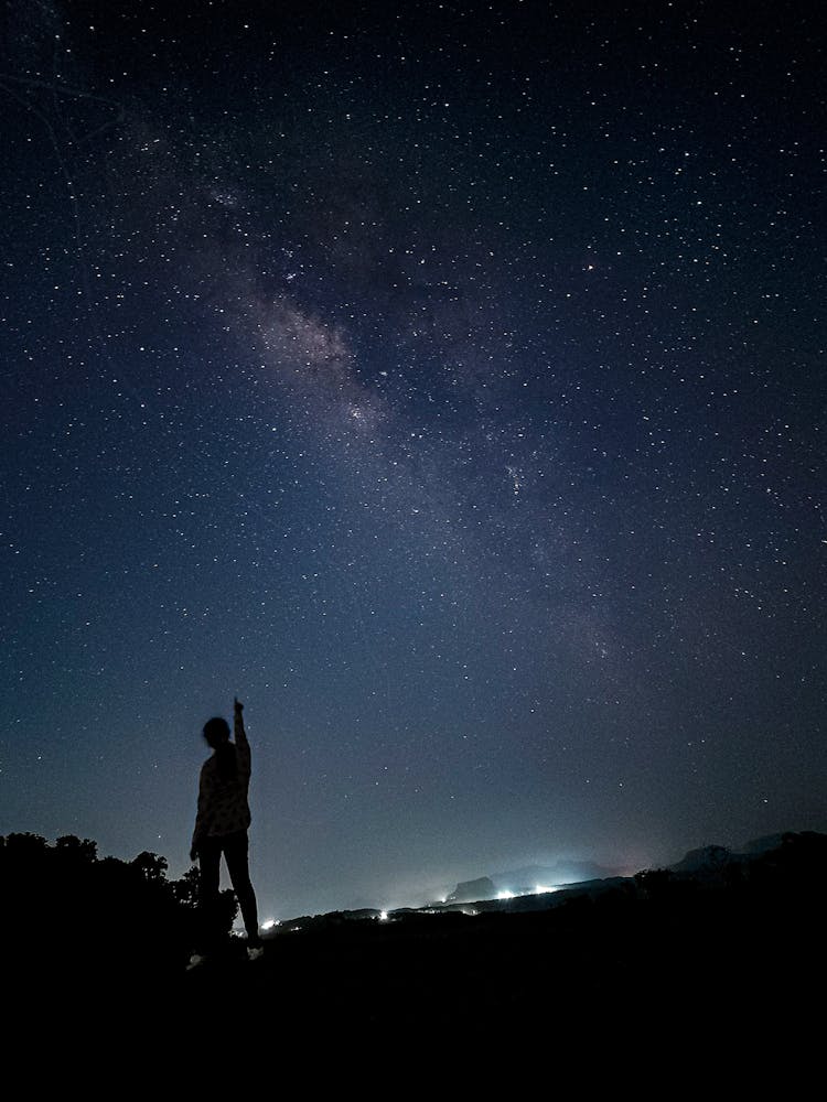 Silhouette Of Person Standing Pointing Finger On Starry Night