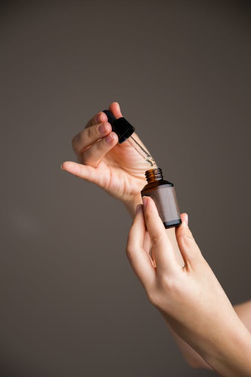 Hands Measuring Oil From Bottle