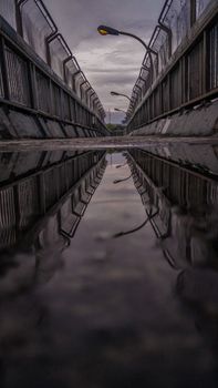 Moody reflection scene of street lamps on an urban bridge after rain.