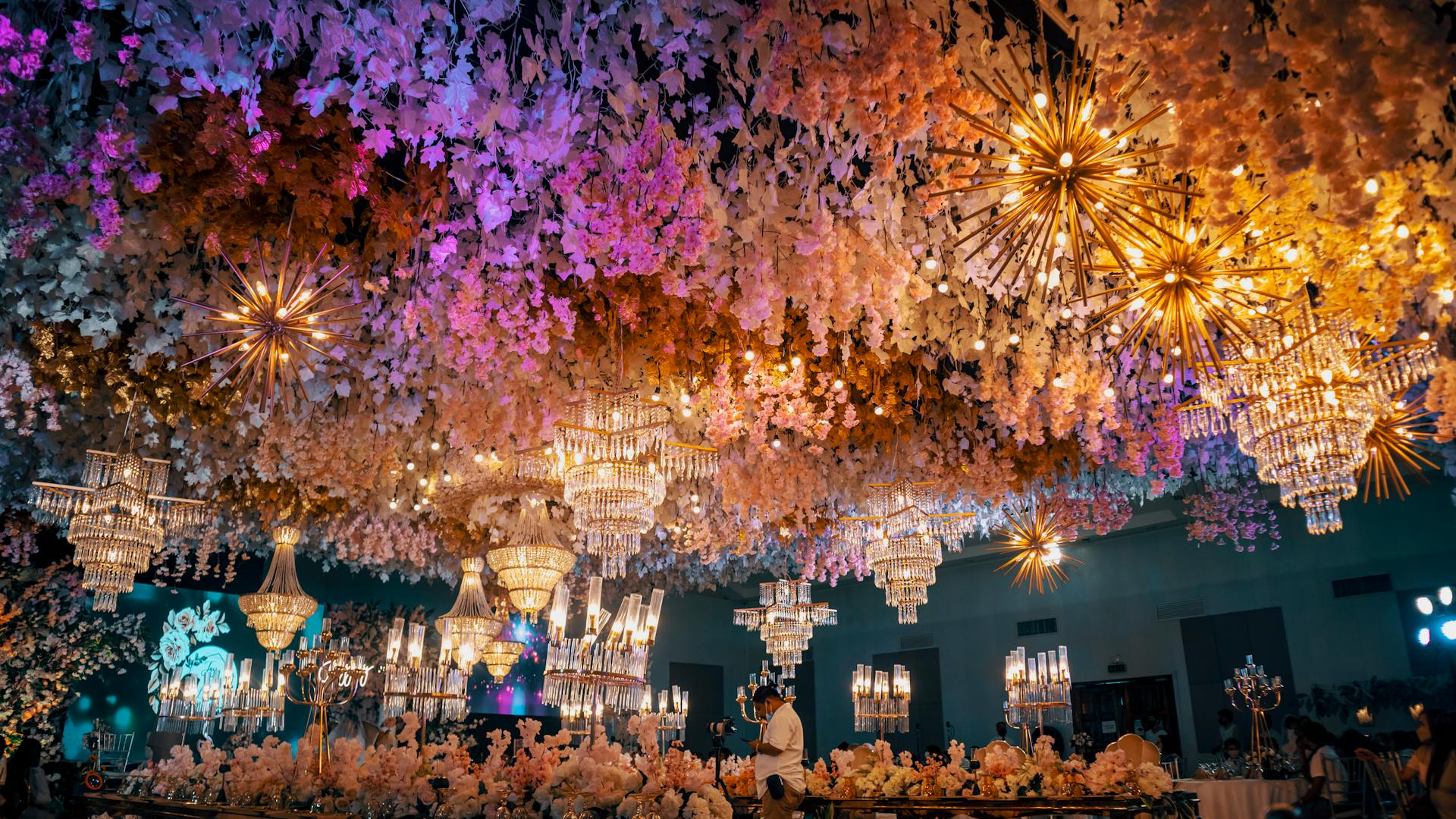 Captivating wedding venue adorned with floral decor and dazzling chandeliers, creating a magical ambiance.