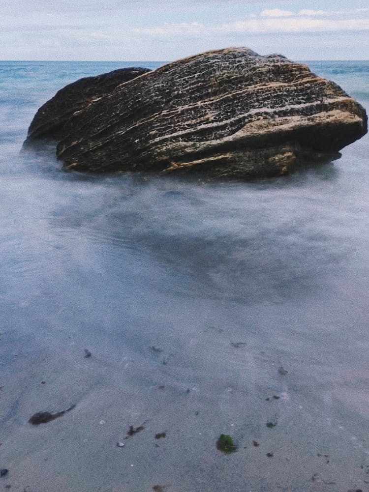 Photo Of A Rock Standing Into The Water