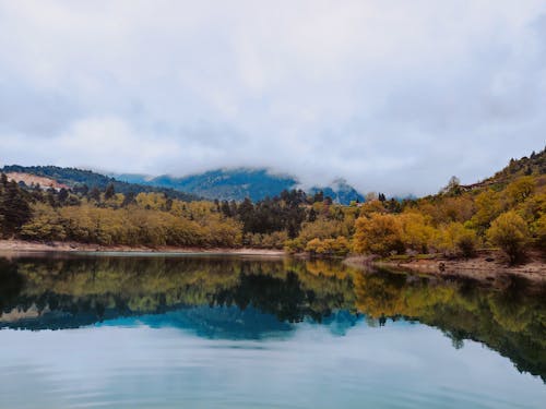 Free Lake Near Autumn Trees and Mountain Covered with Low Clouds Stock Photo