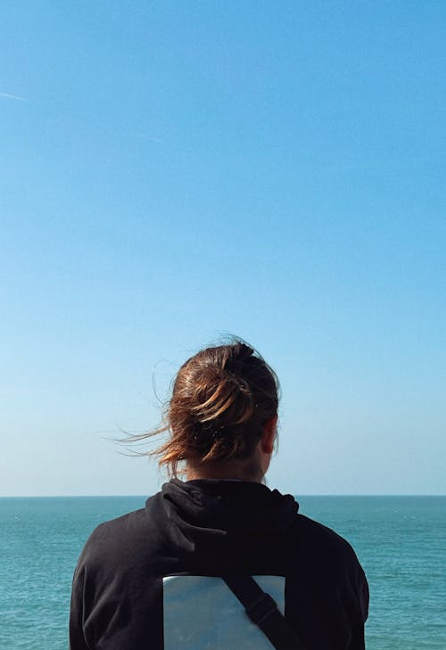 Back View of a Person Standing in Front of the Ocean