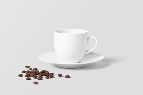 Free A simple white coffee cup with saucer and scattered roasted coffee beans on a white background. Stock Photo
