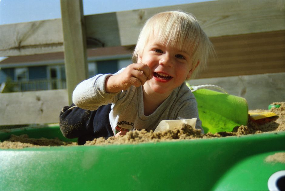 A joyful child playing in a sandbox outdoors, enjoying the sunny day.