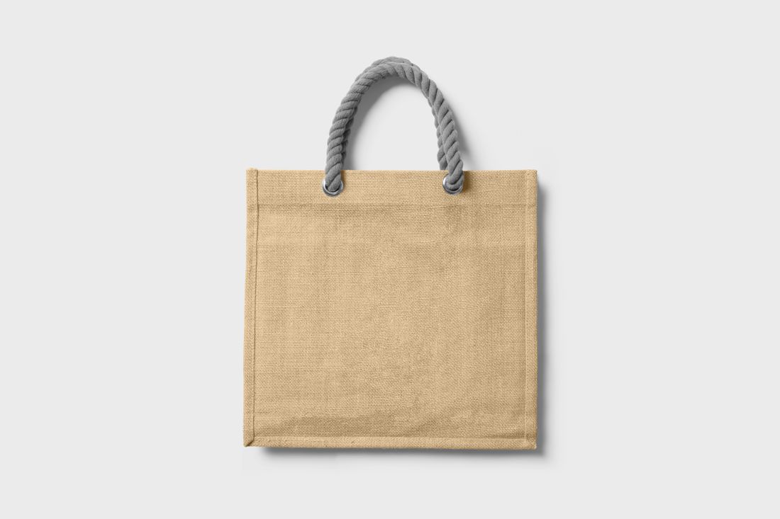 A plain undyed jute tote bag with rope handles on a white background