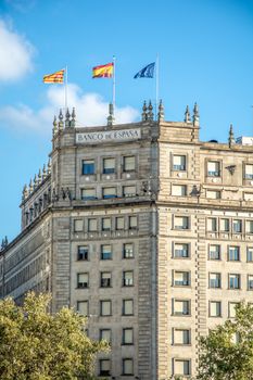 High-rise Banco de España building with flags on a sunny day.