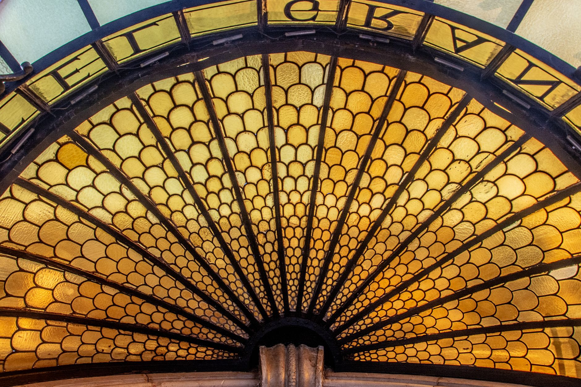 Elegant stained glass window with geometric fan pattern and warm hues.. elegant, stained, glass
