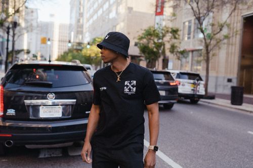 Free Stylish man in casual streetwear crossing a busy urban street, capturing modern city life. Stock Photo