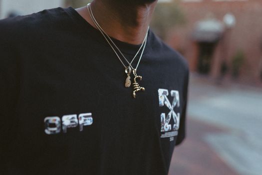 A close-up shot of chic necklaces on a black shirt worn outdoors, showcasing urban fashion.