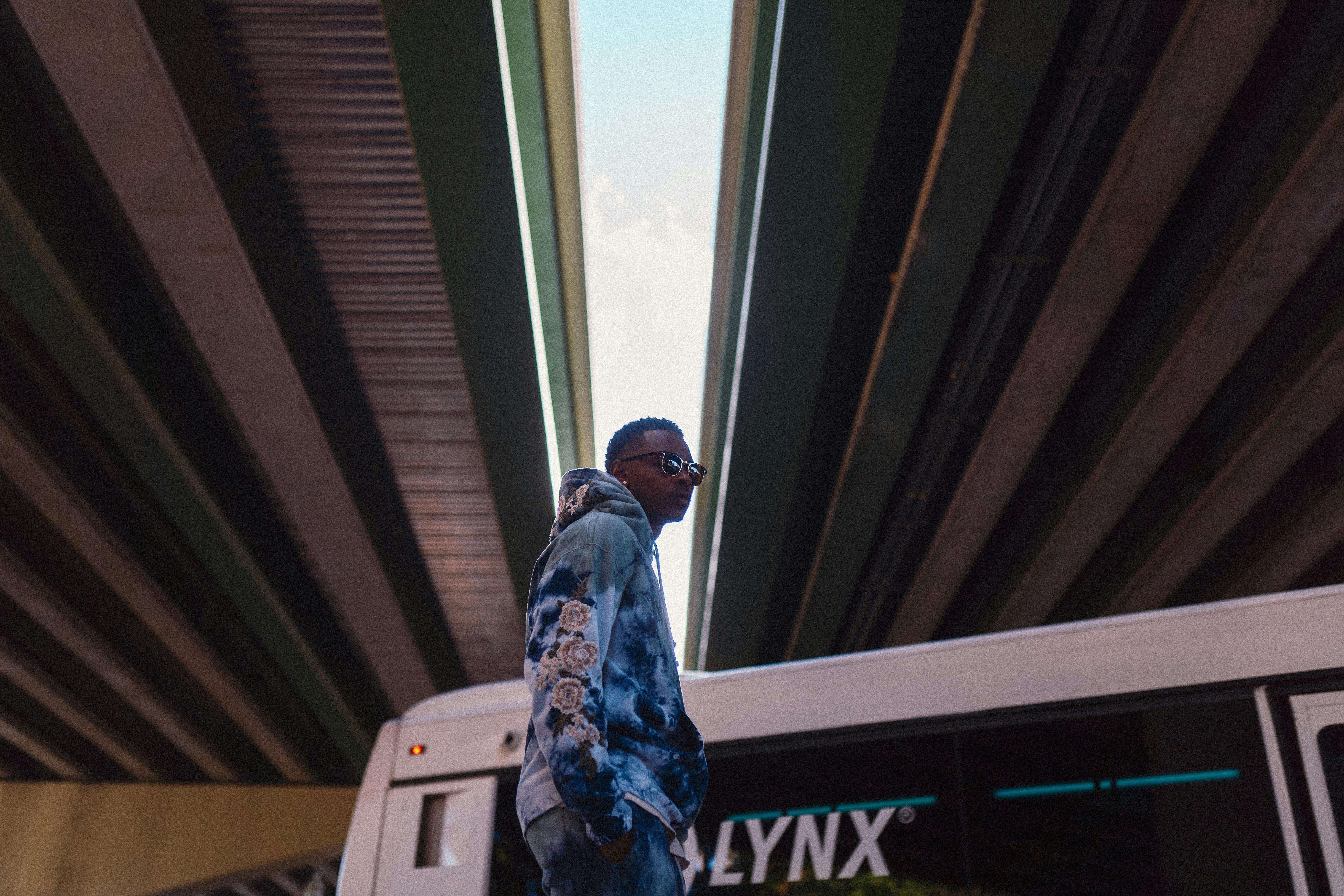 Free Stylish young man in tie-dye hoodie under city bridge showcasing urban fashion. Stock Photo