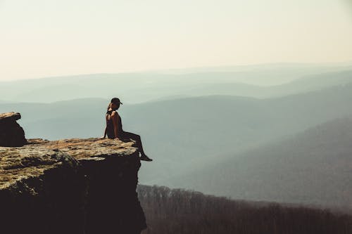Free Woman Sitting on Edge of Rock Formation Stock Photo