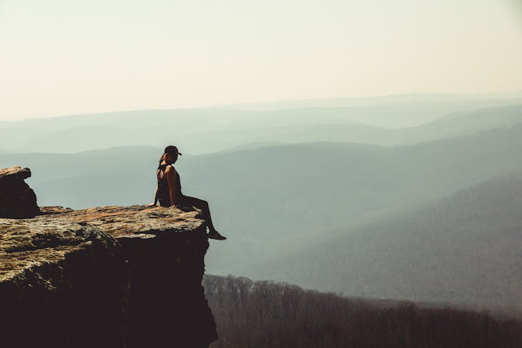 Woman Sitting On Edge Of Rock Formation