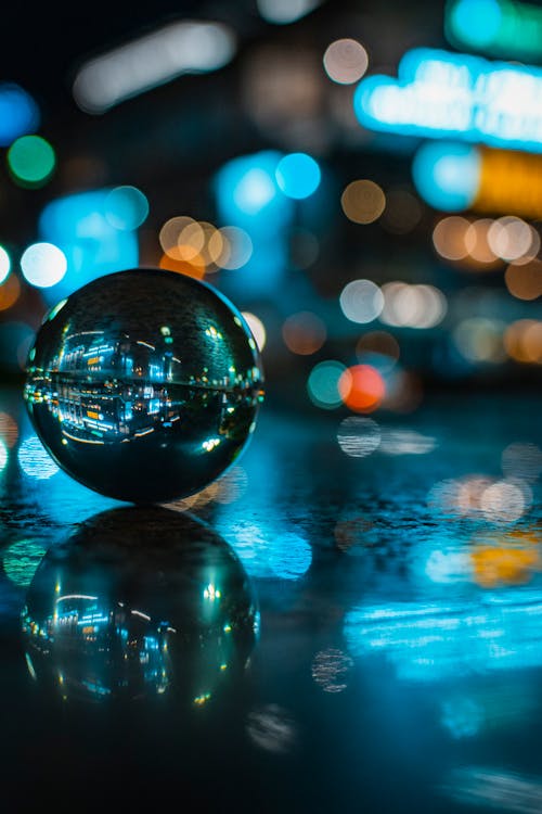 Стеклянный шар с отражением освещенного здания