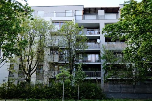 Free Contemporary urban apartment building enveloped by lush green trees and bushes. Stock Photo