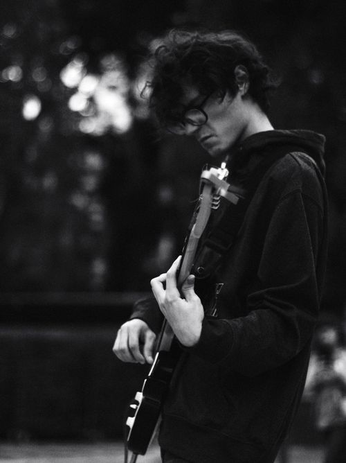Free Black and white photo of a young musician passionately playing an electric guitar outdoors. Stock Photo