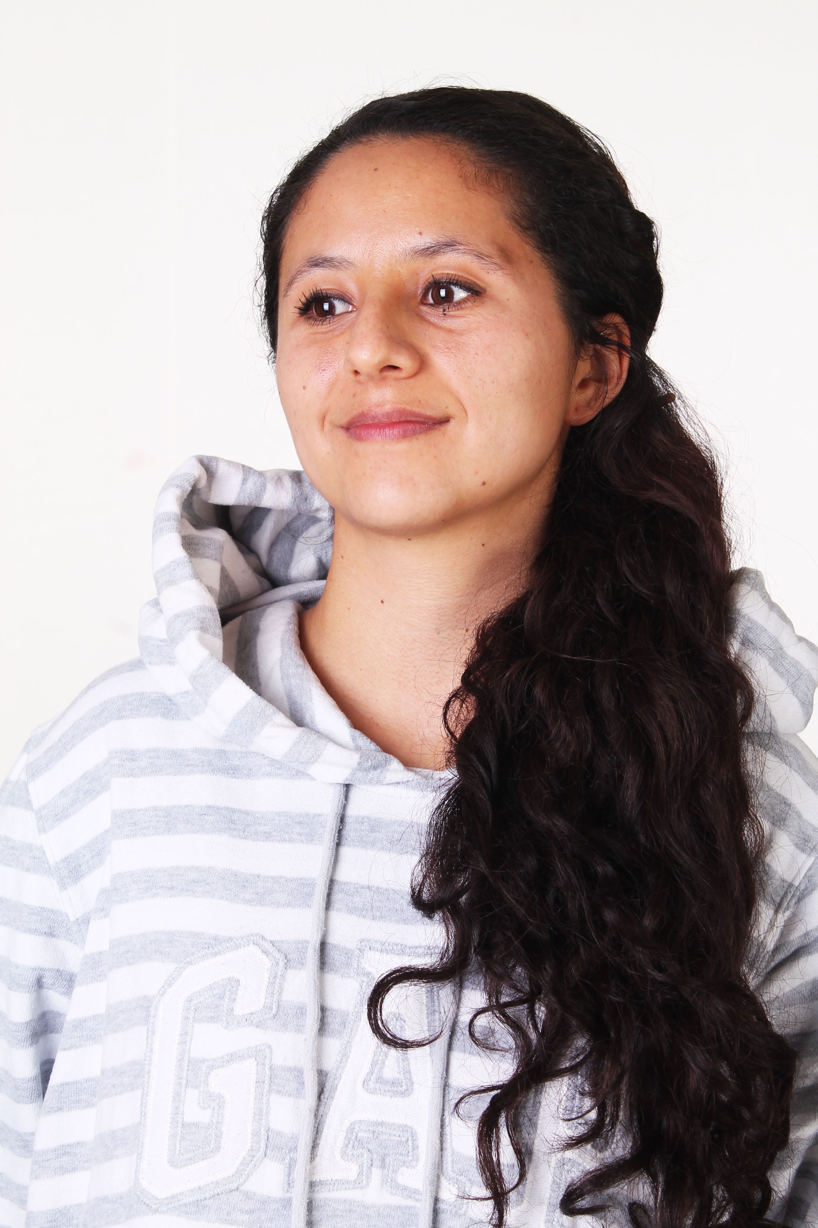 Portrait of a Hispanic woman in a striped hoodie with a subtle smile, captured in a studio setting.