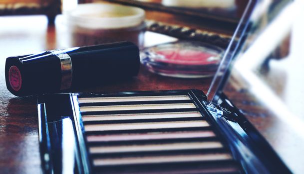 A collection of makeup products including lipstick and eyeshadow on a wooden table, perfect for beauty themes.