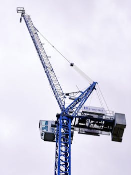 Low angle view of a tower crane reaching into a cloudy sky, highlighting construction in London.