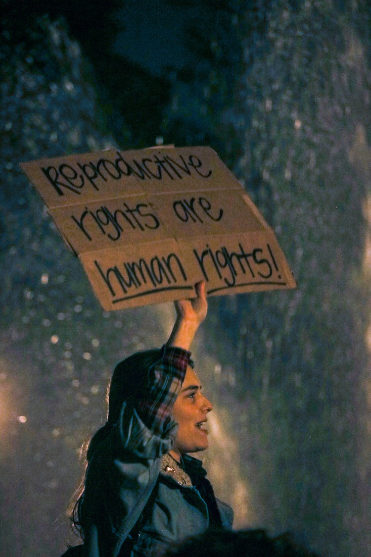 Woman Holding Cardboard Sign Saying Reproductive Rights Are Human Rights