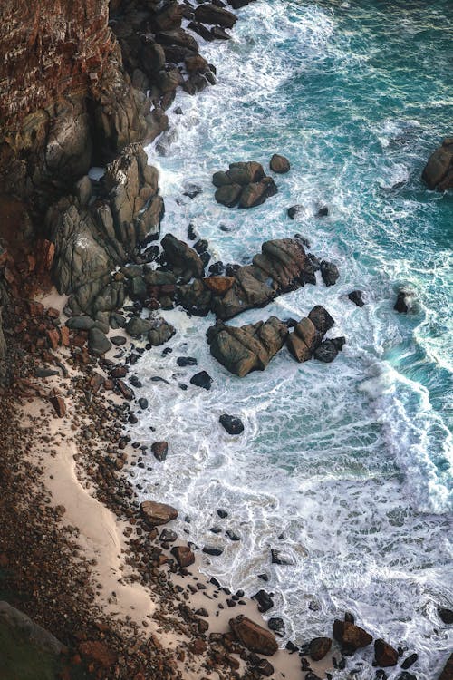 A High Angle Shot of Ocean Waves Crashing on Rocky Shore