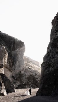Bride and groom walk hand in hand through dramatic cliffs, symbolizing love and unity.