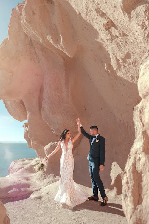 Newlywed Couple Standing at the Foot of Rock Formation 