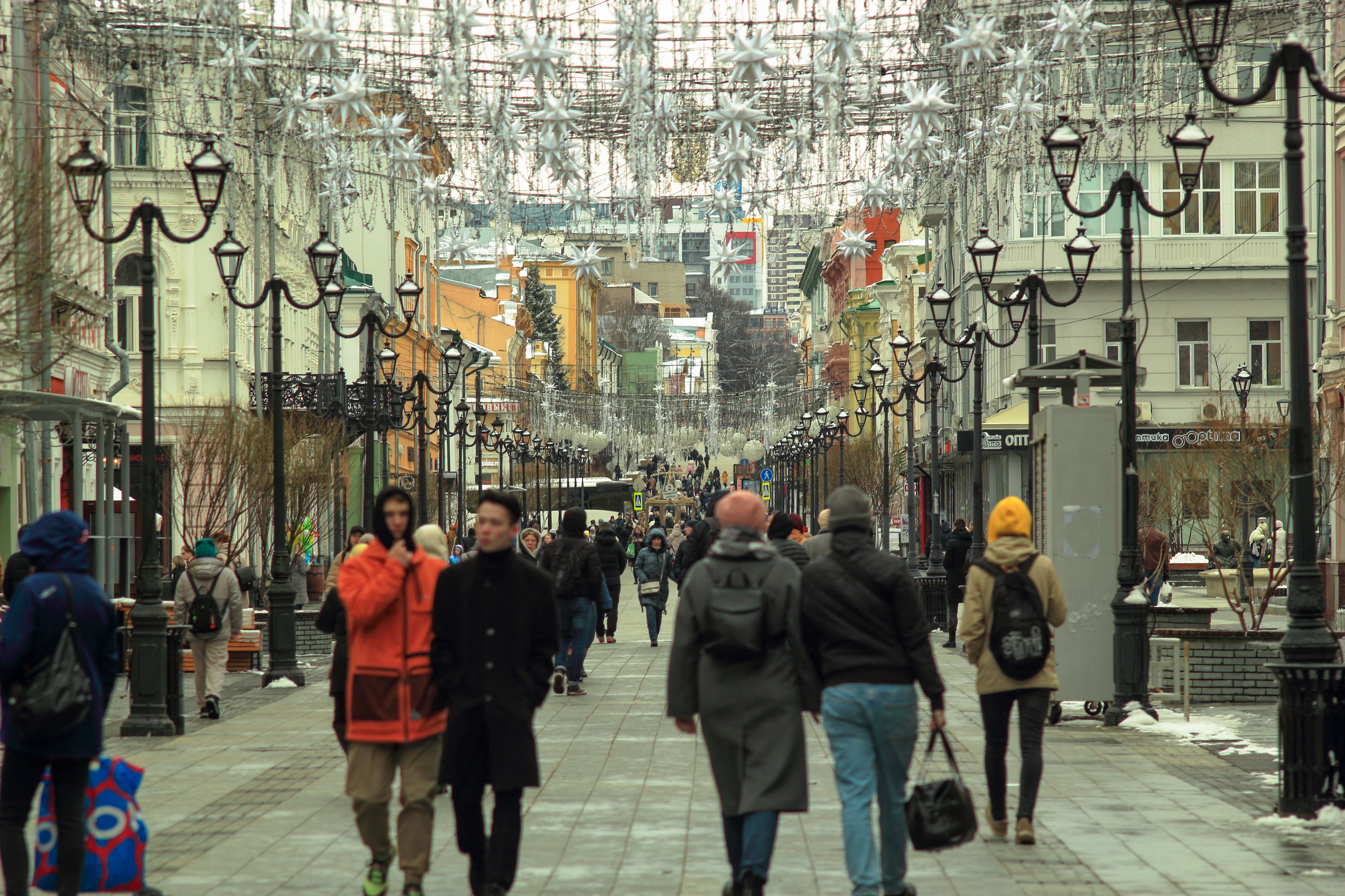 People walking on a pedestrian street in Nizhny Novgorod, Russia during winter with decorative lights.