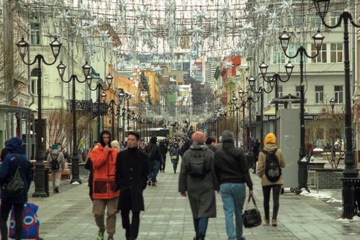 People walking on a pedestrian street in Nizhny Novgorod, Russia during winter with decorative lights.