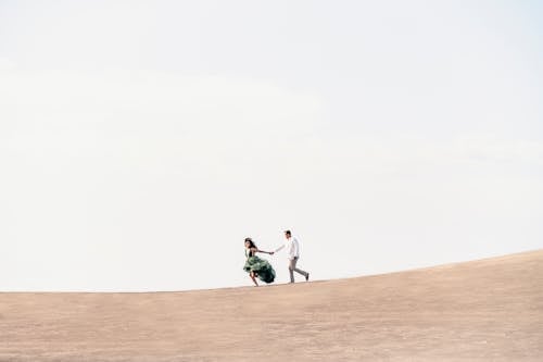 A Couple Holding Hands and Running