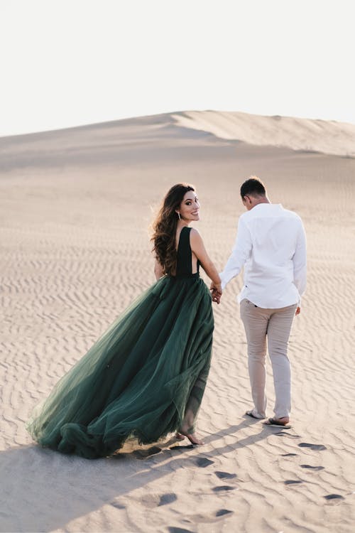 Young Couple Holding Hands and Walking on Sand