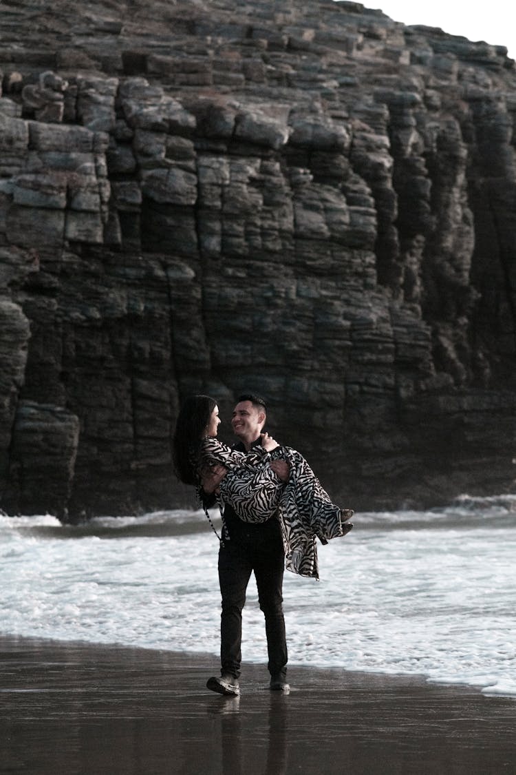 Happy Man Holding Woman In Arms At Beach