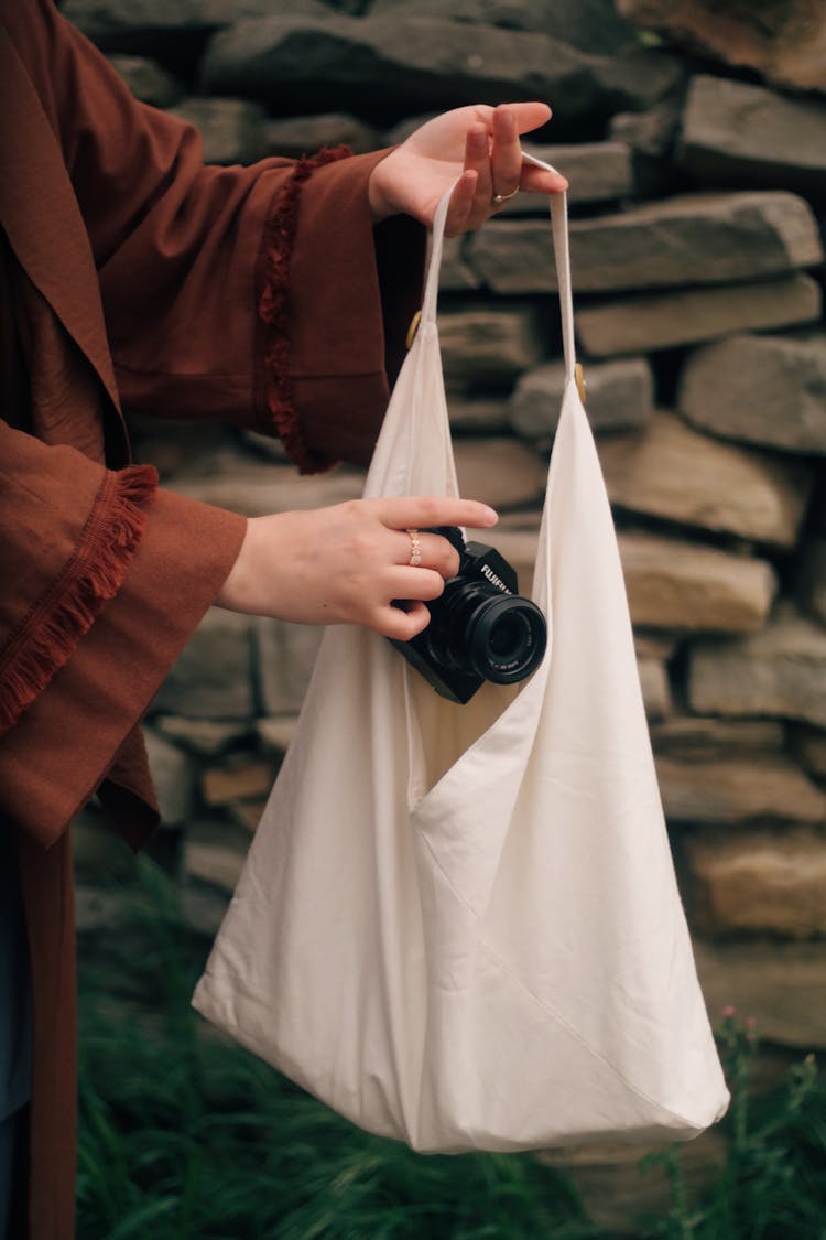 Hands Putting Analog Camera Inside Tote Bag