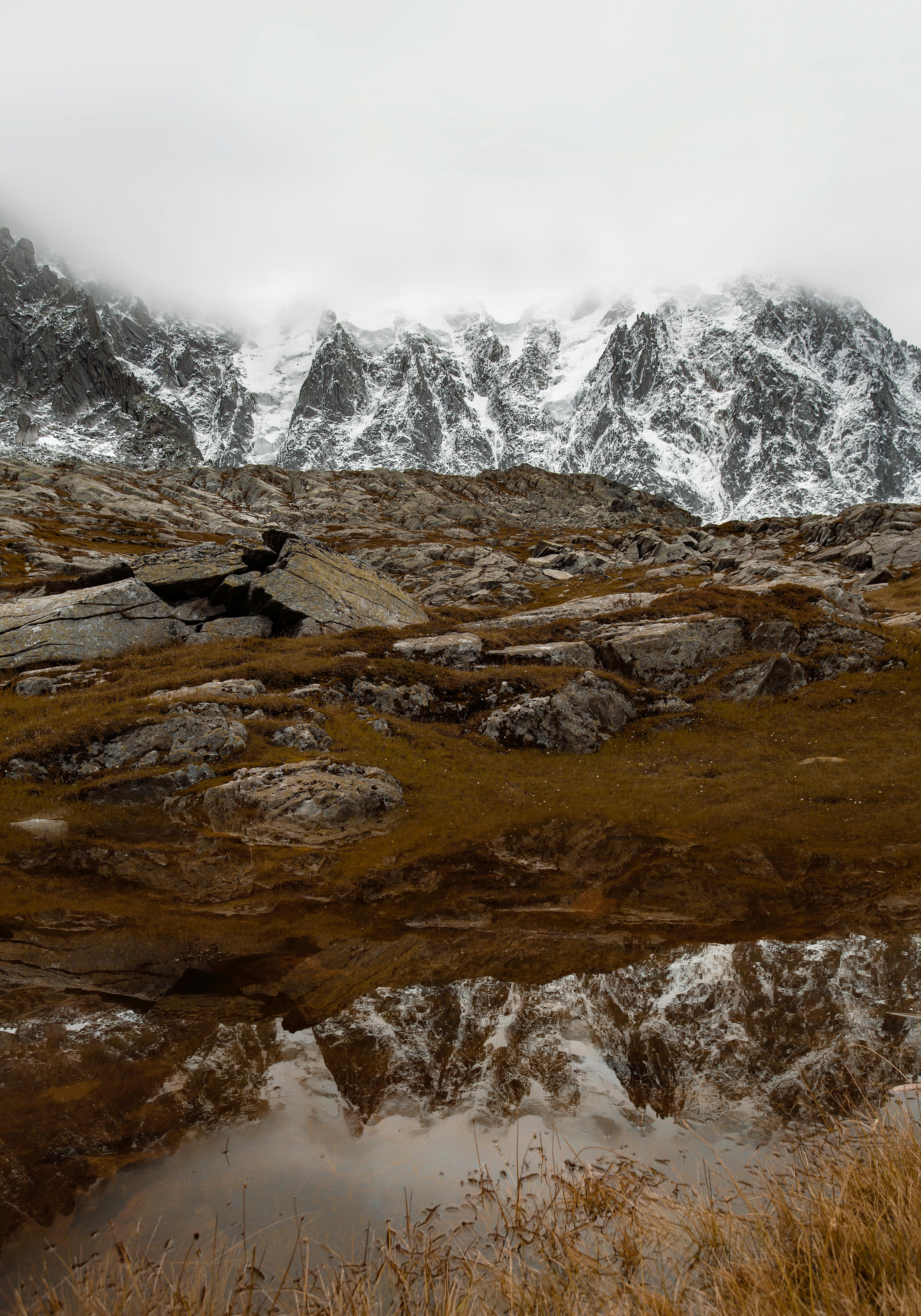 Snow-capped mountains reflected in a tranquil alpine pond in Chamonix, France.