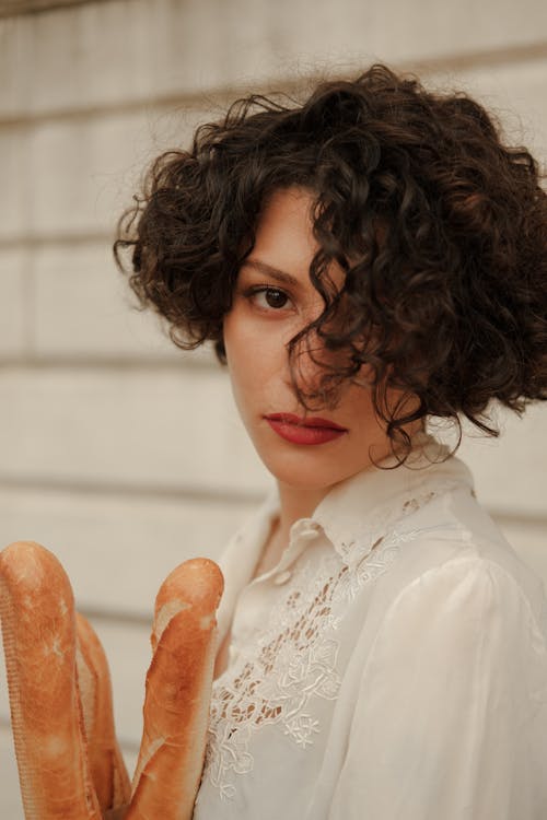 Photo of a Woman with Curly Hair Holding Bread