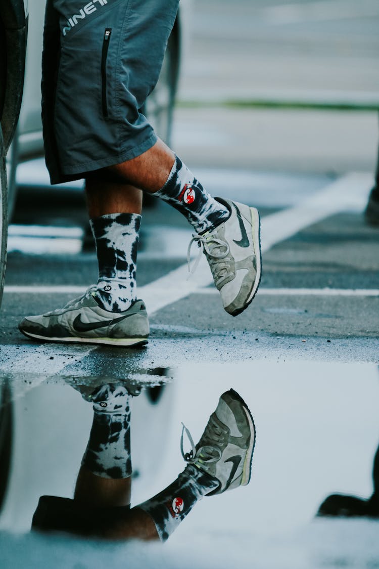 Reflection In Puddle Of Man Legs In Sneakers