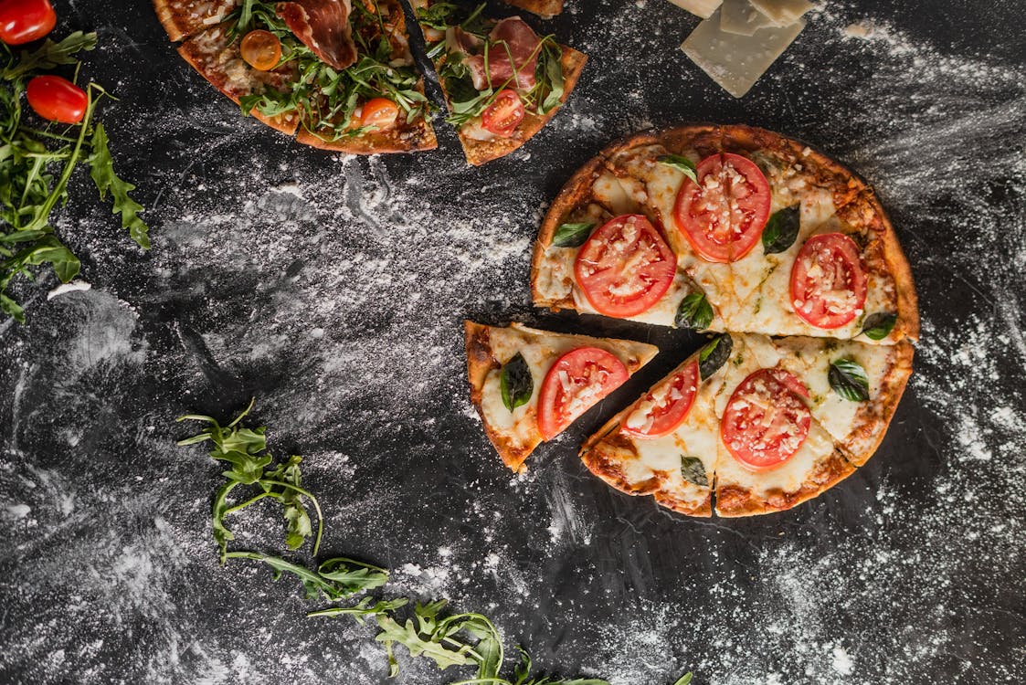 Pizza With Tomato and Green Leaves on Black Surface 