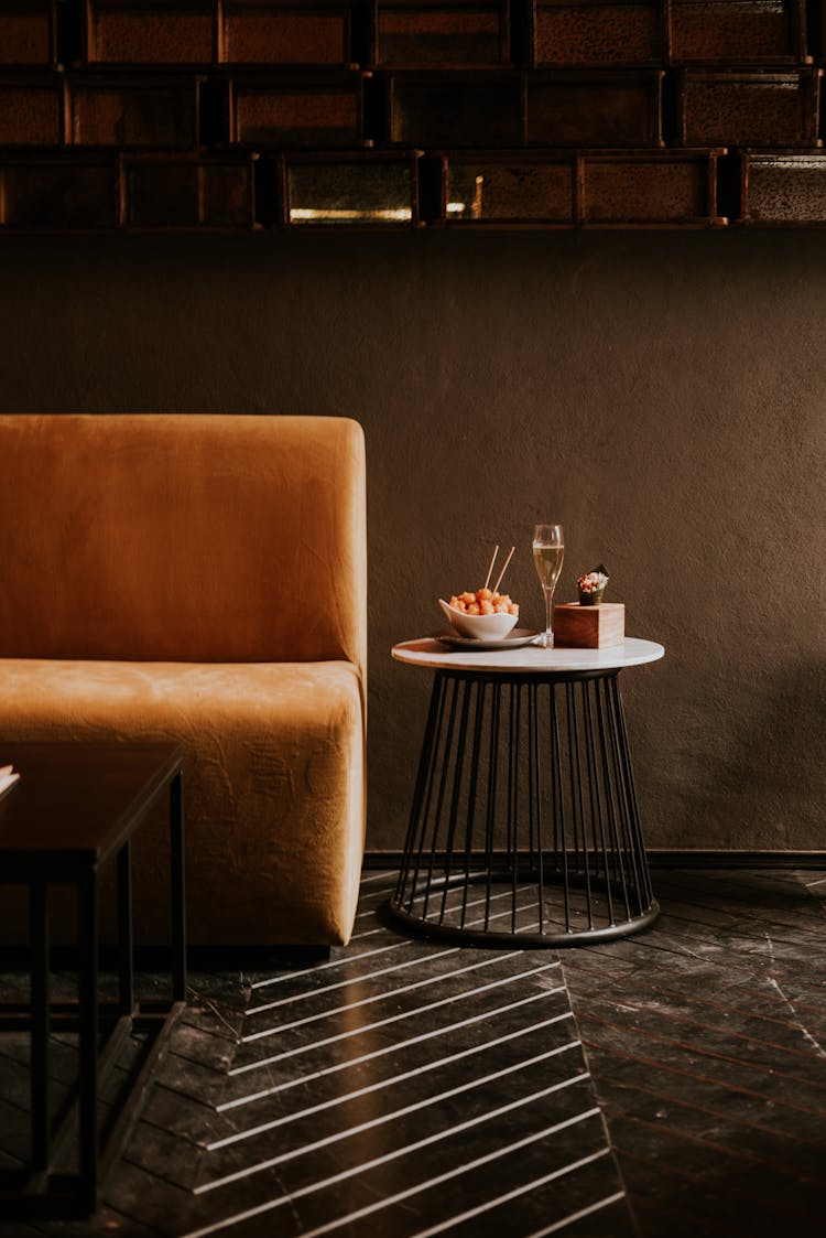 Snacks And Glass Of White Wine Served In Restaurant On Small Round Table