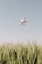 White Drone Flying over Green Grass Field