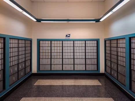 Rows of locked postal mailboxes in a post office interior with overhead lighting.