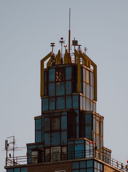 Free Close-up of a modern skyscraper's top with antenna structures against a clear sky. Stock Photo