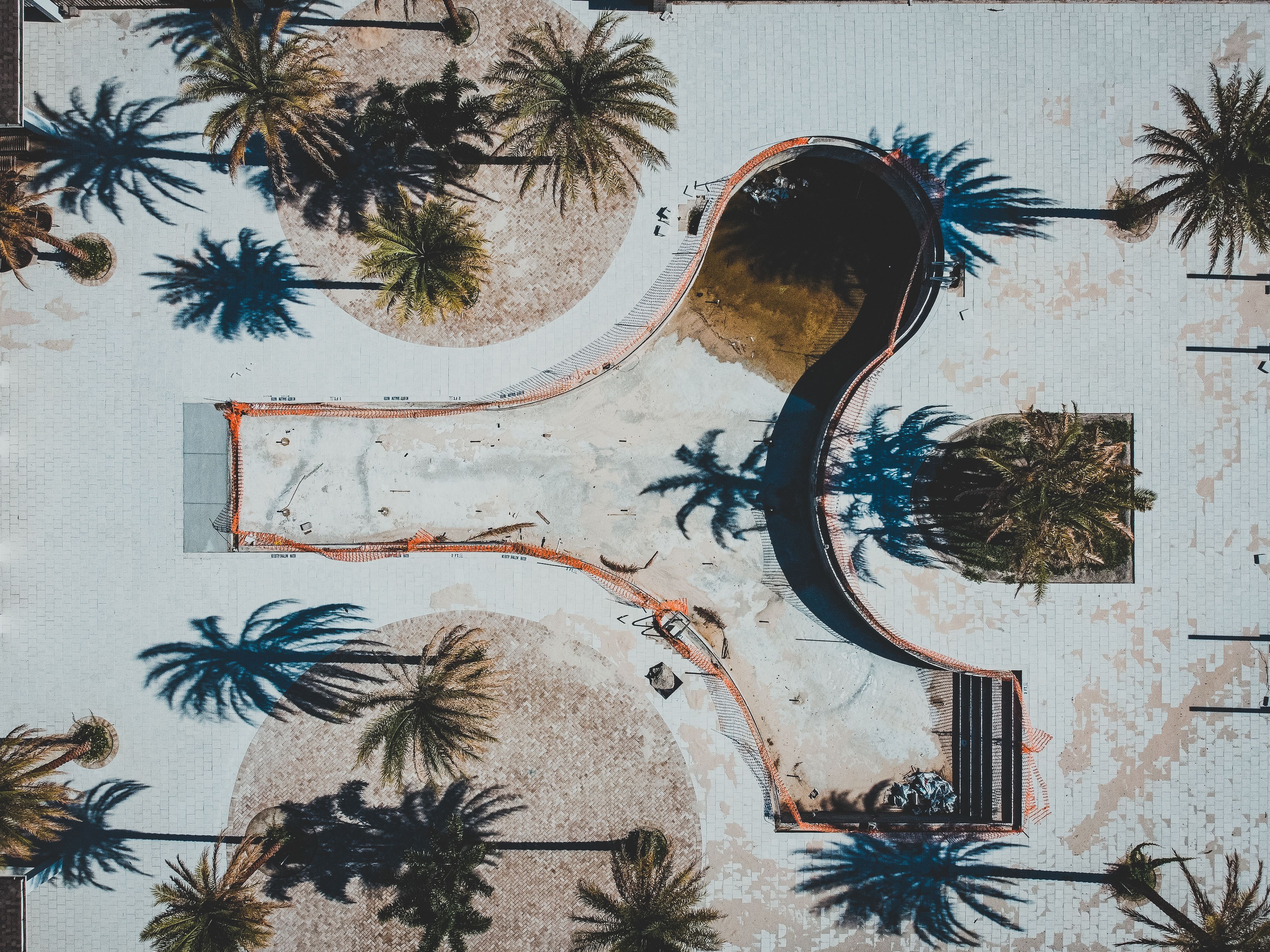 Aerial shot of an empty swimming pool in Winter Springs, Florida, highlighted by surrounding palm trees casting long shadows.