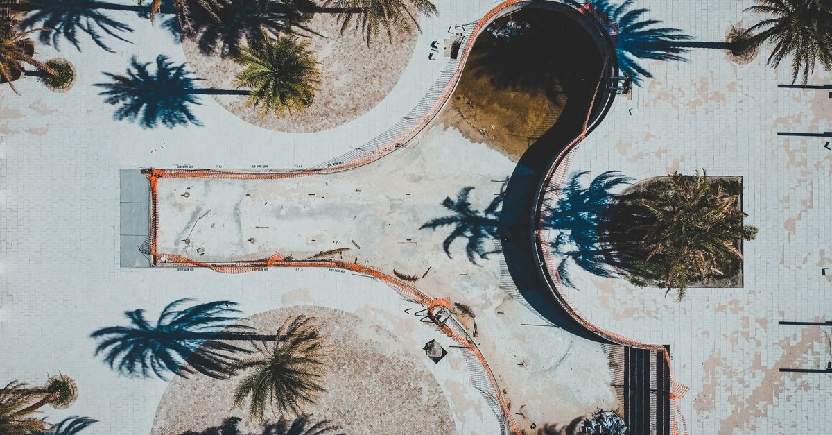Aerial shot of an empty swimming pool in Winter Springs, Florida, highlighted by surrounding palm trees casting long shadows.