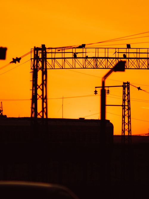 Free Striking silhouettes of tower cranes against a vibrant orange sunset sky. Stock Photo