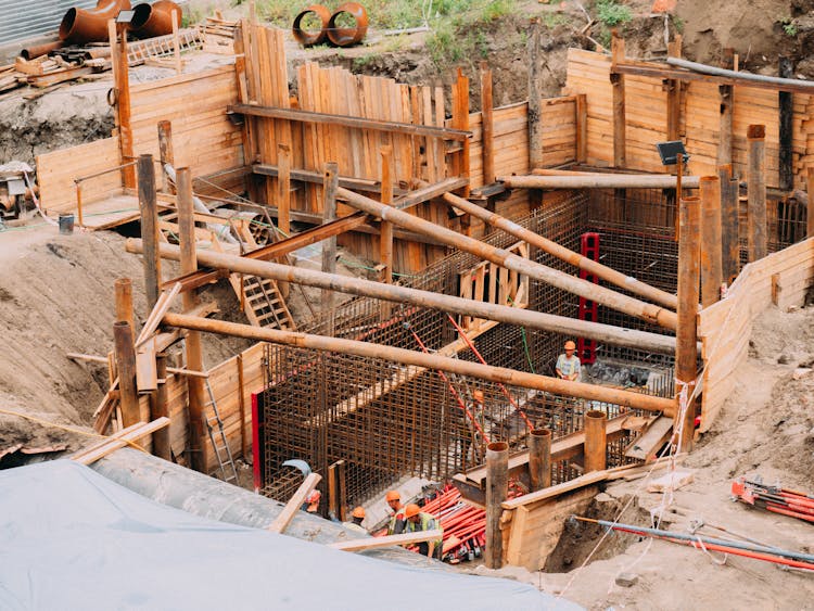 A Group Of People With Hard Hats Working On A Structure With Wooden Fence