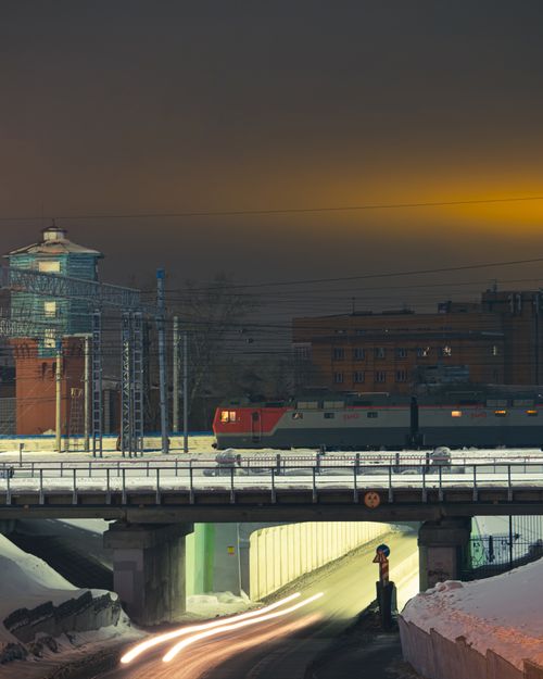 Free A vibrant city night scene featuring a train on a bridge with snow-covered streets below. Stock Photo